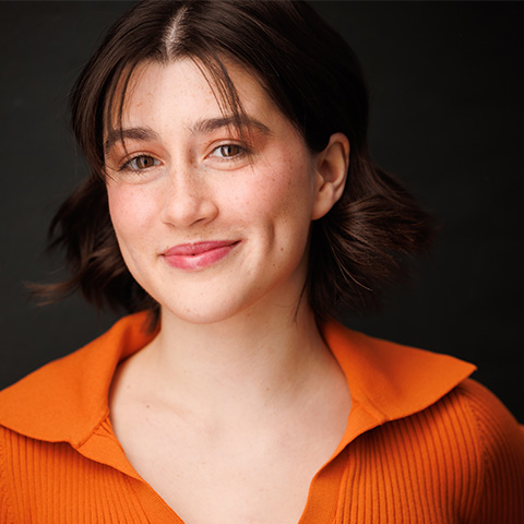 AnnElese Galleo headshot: smiling in orange shirt with collar