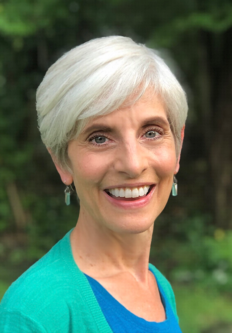 Andrea Southwick headshot: Andrea is smiling and wearing a teal sweater and dark blue shirt with trees in the background.