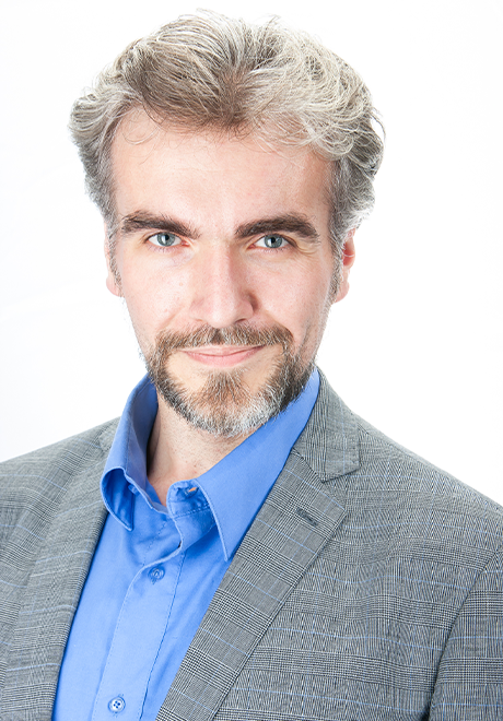 Alexandr Polyakov headshot: in gray suit and blue shirt
