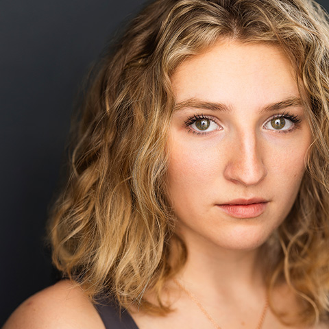 Sarah Kalafos headshot: in front of dark blue wall