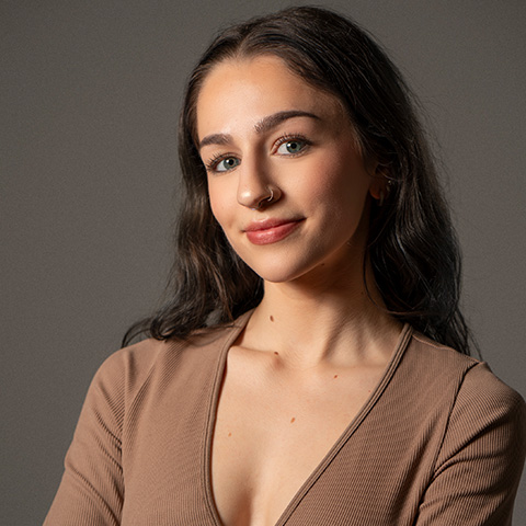 Alexis Tsiramanes headshot; smiling in a brown v-cut blouse