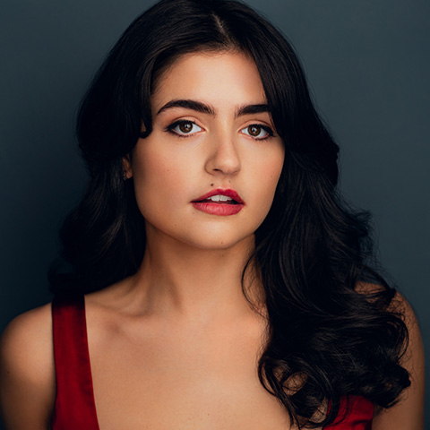 Stevie Bullard headshot: wearing a red tank top in front of a dark blue wall