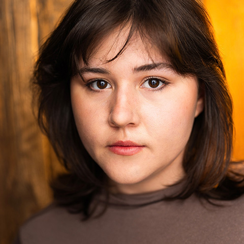 Meghan Carey headshot: in brown shirt in front of orange wall