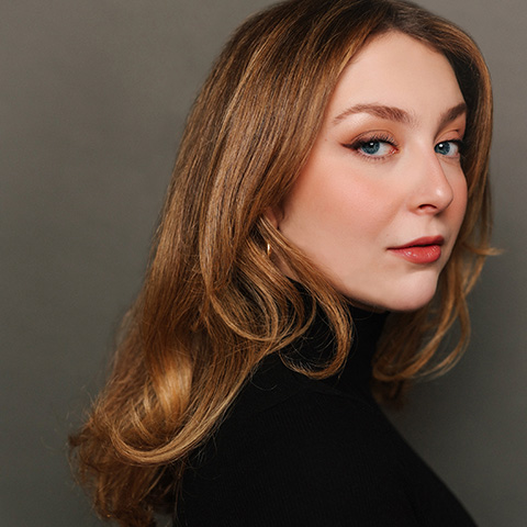 Hannah Chiappine headshot: wearing a black shirt in front of a gray wall