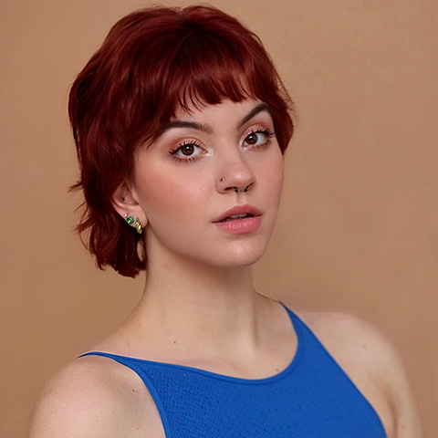 Carly Corsitto headshot: wearing a blue tank top in front of a brown/beige background