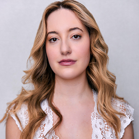 Emma Kops headshot: wearing white shirt in front of light grey wall