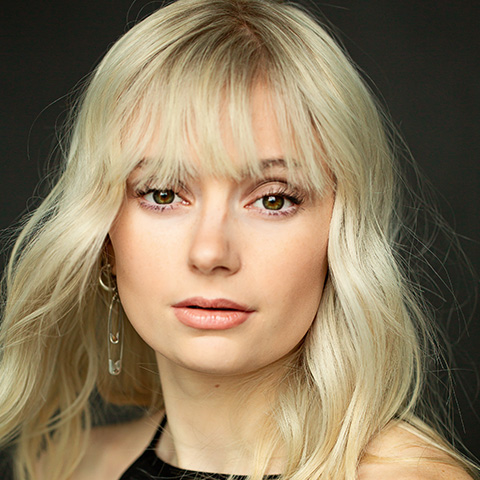 Allison Gann headshot: in black top in front of black background