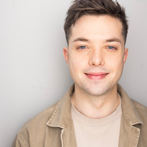 Avery Horton headshot: wearing beige jacket with off-white shirt in front of white wall