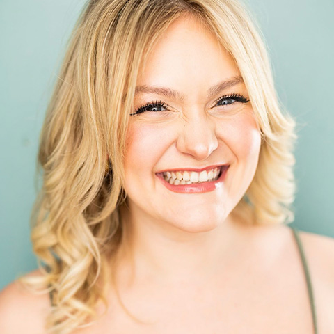Kaylee Kay headshot: smiling in front of blue wall
