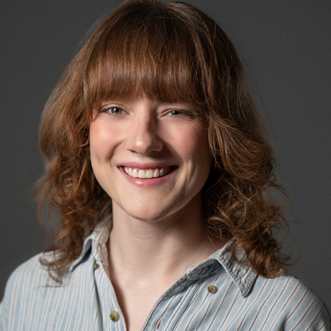 Kate Warner ehadshot; smiling and wearing a gray button up