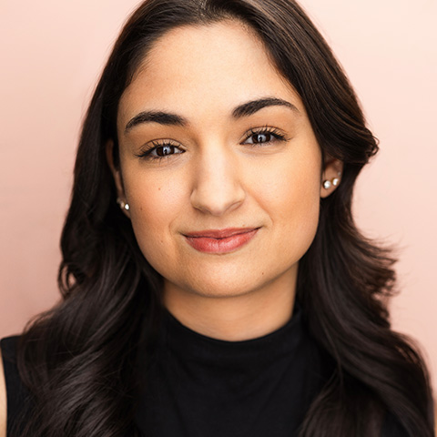 Eleni Kontzamanys headshot: in black shirt in front of pink wall