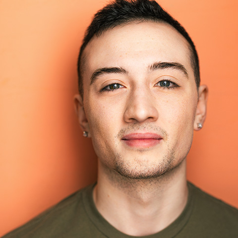 Greyson Lynch headshot: wearing green shirt in front of orange background