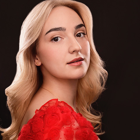 Ella Marcus headshot: wearing red shirt in front of black background