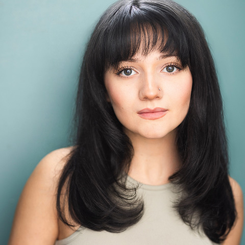 Mikaela McGovern headshot: wearing off white shirt in front of light teal background