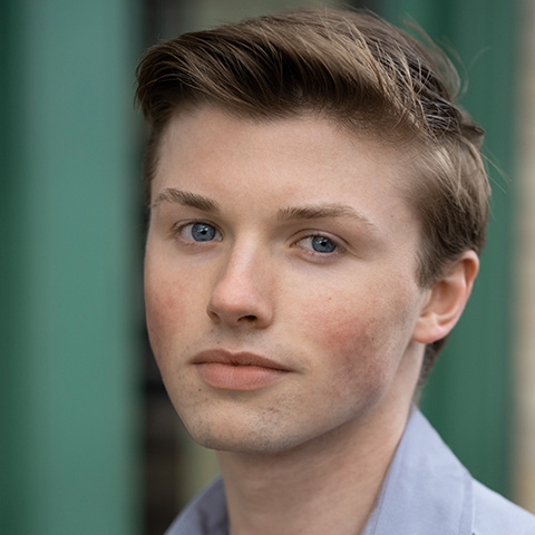 Tyler Moran headshot: in front of green/blue background