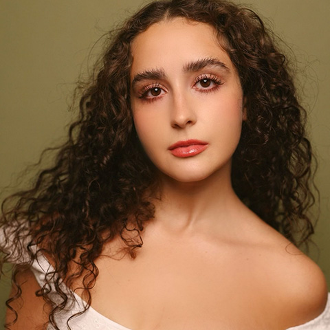 Eeve perez headshot: wearing white top in front of green background