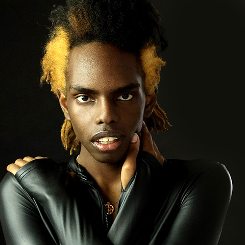 Hammond Samba headshot: wearing dark long sleeve shirt in front of black background