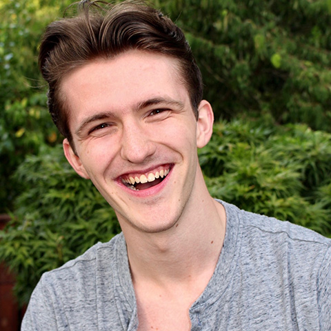 Brendan Sheehan headshot: wearing gray shirt in front of trees