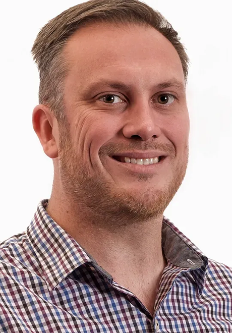 Andy Crawford headshot. Andy is smiling in front of a white background in a dress shirt.
