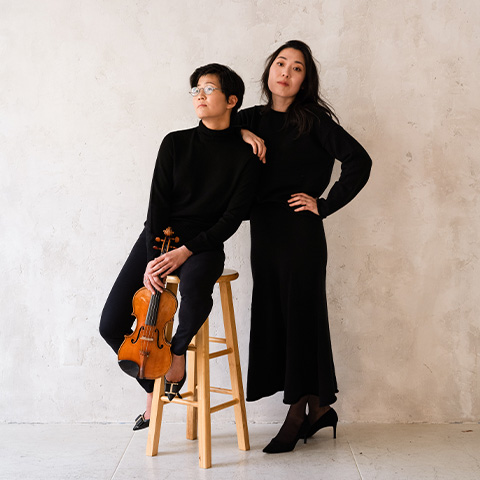 musicians sit in front of a white wall 