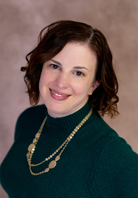 Megan Stahl headshot. Smiling in green shirt with gold chain.