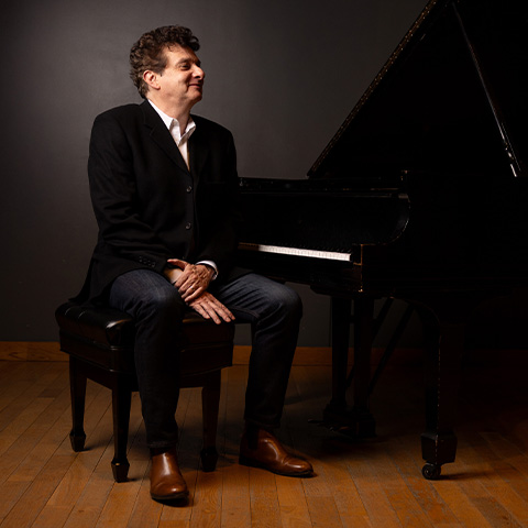 Pierre Hurel sitting by a grand piano with the lid up