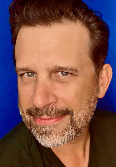 Brian Avers headshot: smiling in front of blue background.