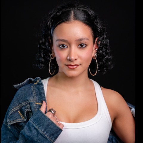 Kena Ruiz Ransom headshot: wearing a denim jacket off the shoulder with a white tank top in front of a black background