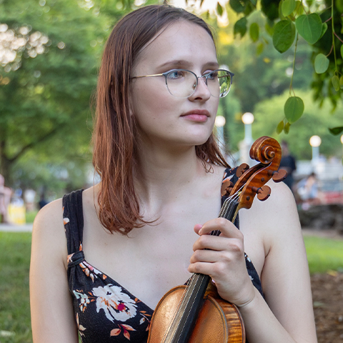 Lauren Oeser headshot, holding violin looking off into the distance
