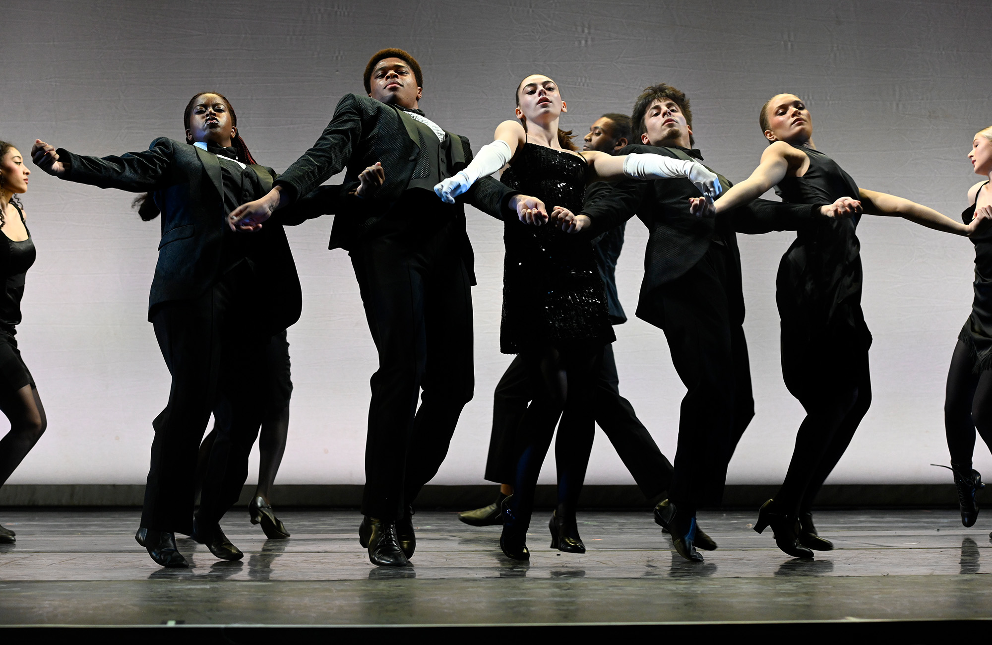 Dance students performing on stage in black outfits