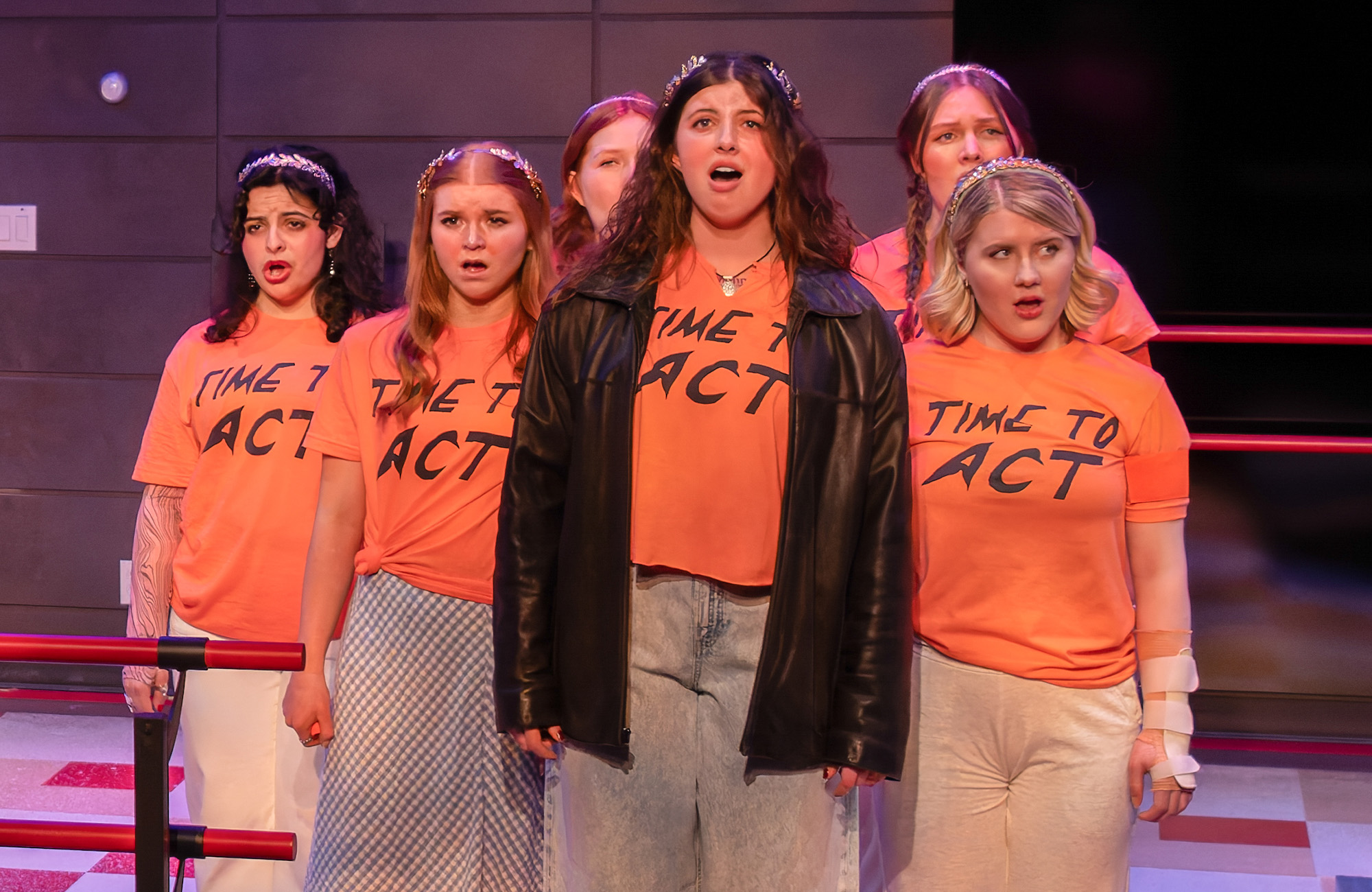 Performers in 'Time to Act' singing together in orange shirts