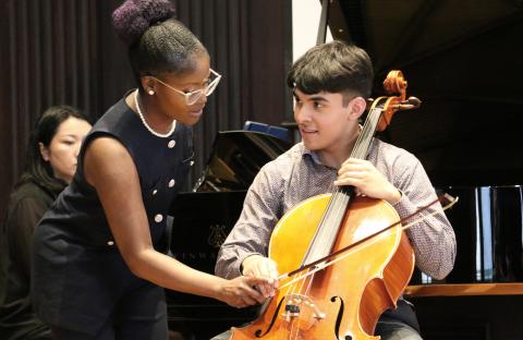 Associate Professor Patrice Jackson assists a student cellist with his bow grip.